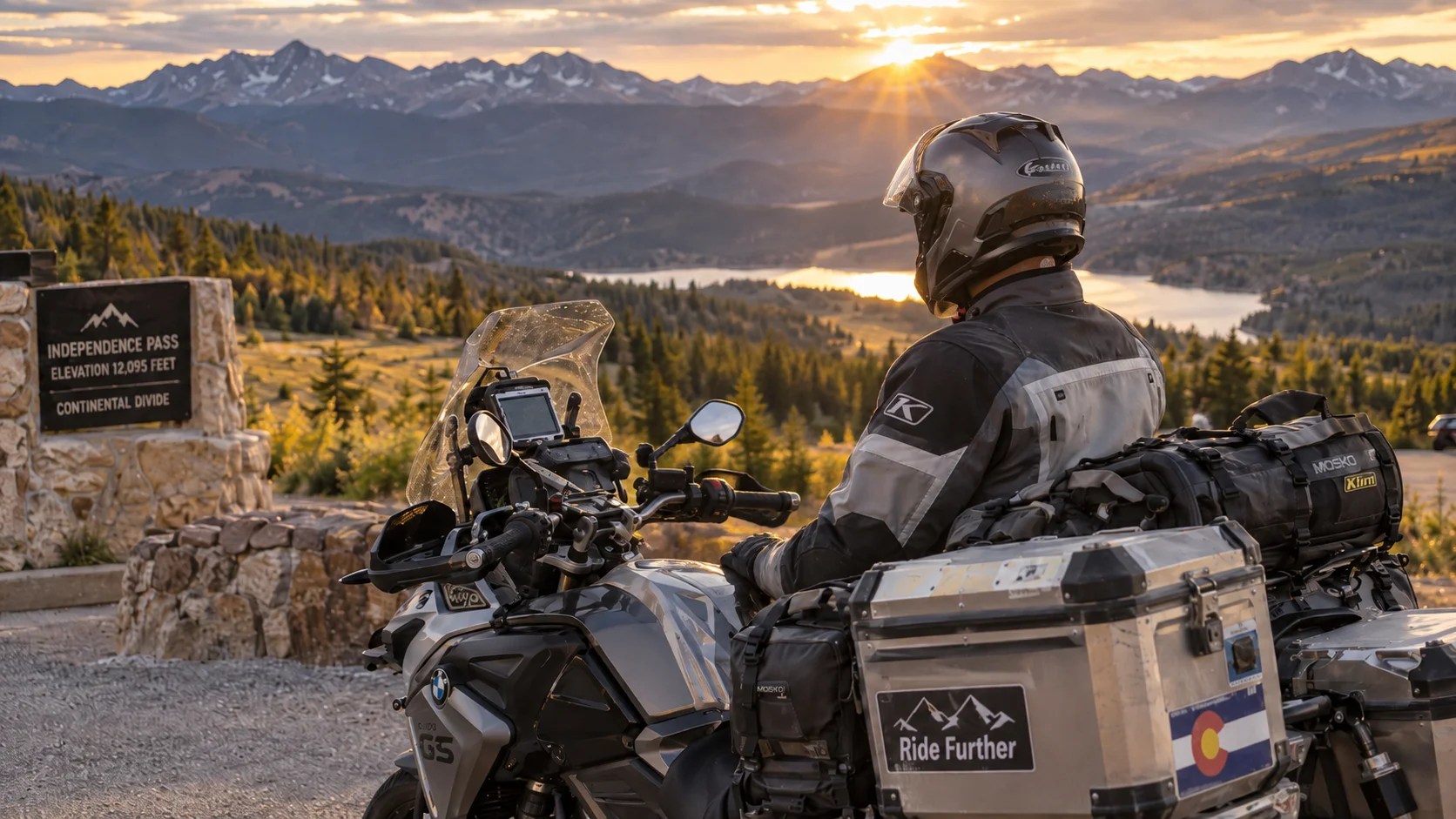 Motorcycle rider overlooking Colorado mountains at Independence Pass beside an adventure bike at sunset.