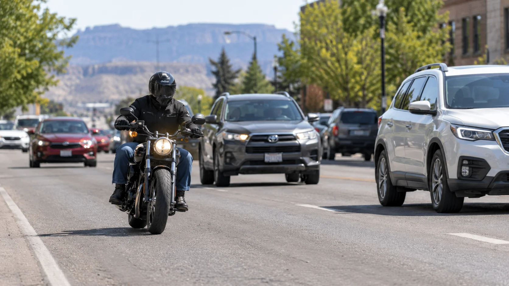 Motorcyclist riding with headlight on in a lawful lane position on a Casper, Wyoming roadway, illustrating Wyoming’s full-lane motorcycle rule.