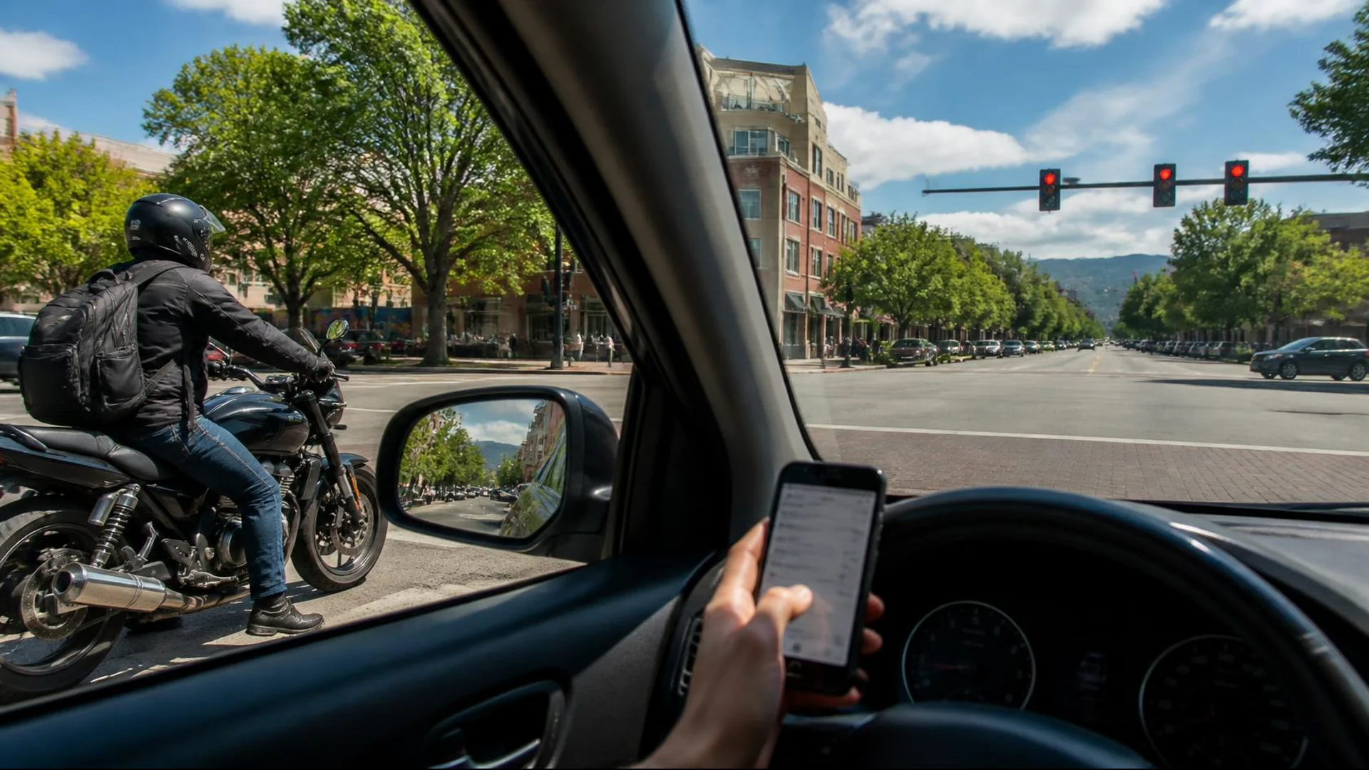 Driver holding a phone near a motorcycle at a Fort Collins intersection