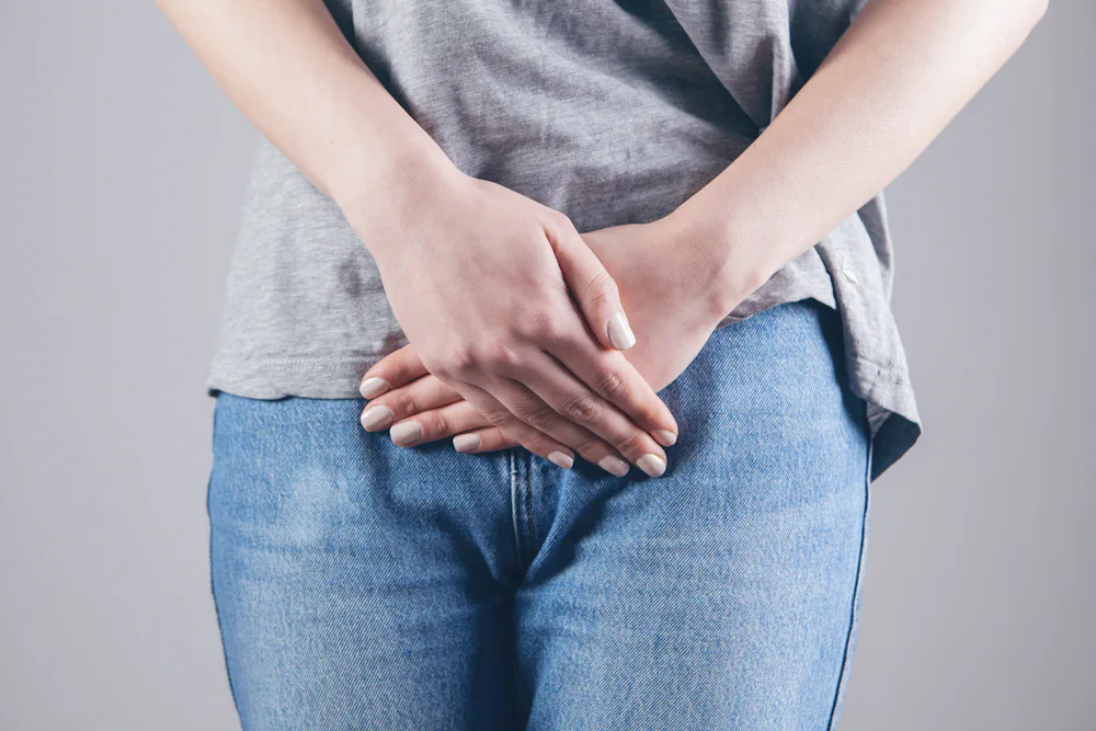 Une personne pose les mains sur le bas de son abdomen.