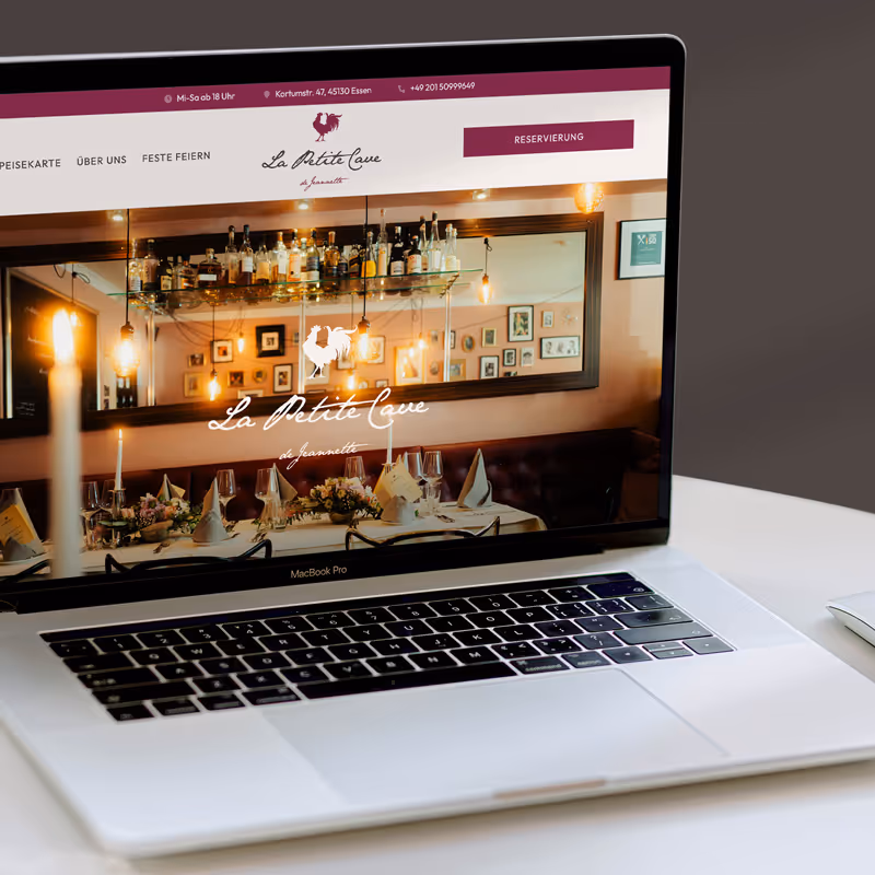 Preview of the La Petite Cave de Jeannette restaurant - web design project by Ruta Dambrauskaite - shown on a MacBook that is placed on a desk