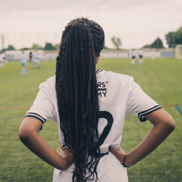 A girl with a football uniform standing on a football pitch