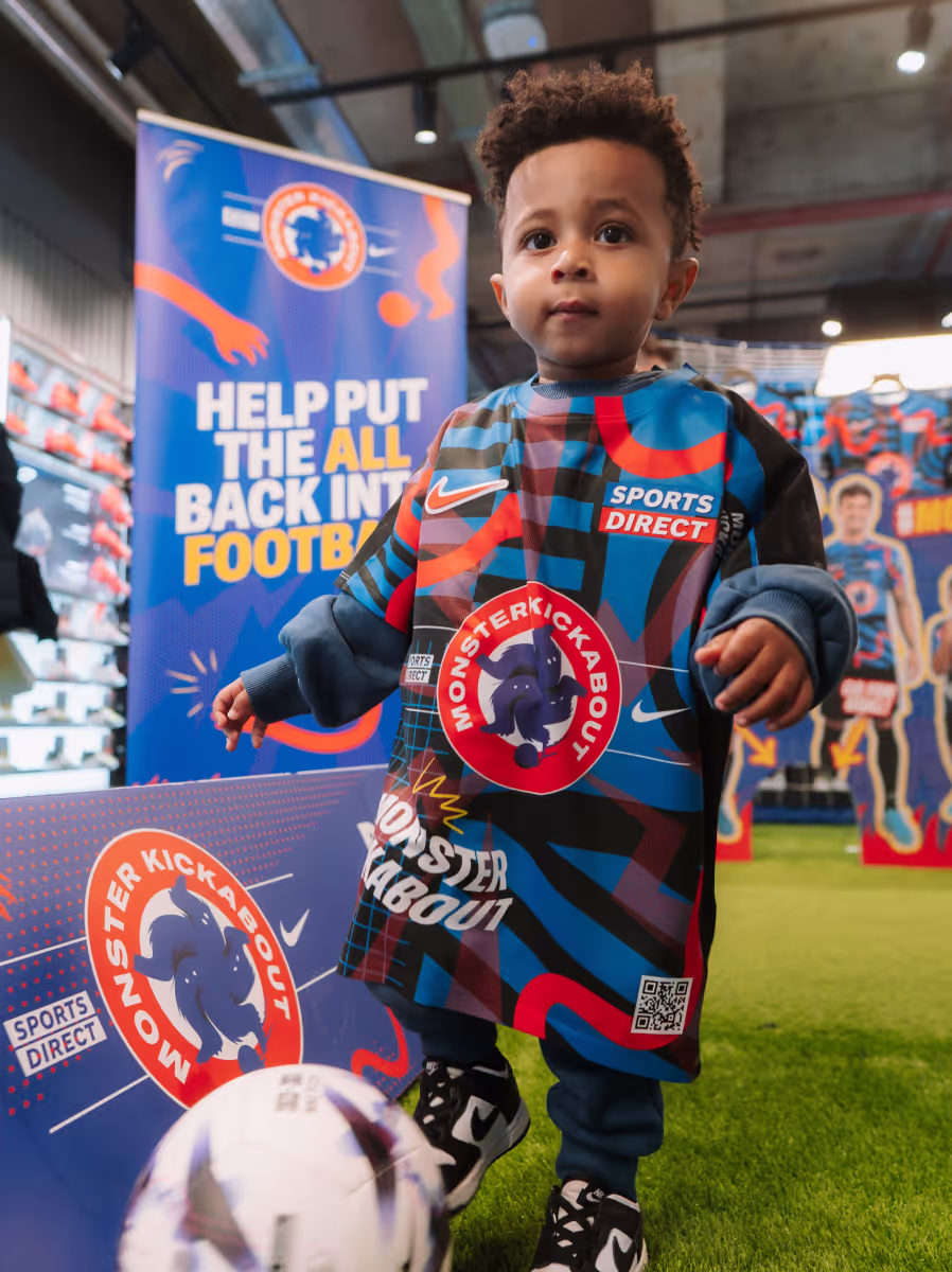 A photograph of a kid playing football wearing little monsters football kit