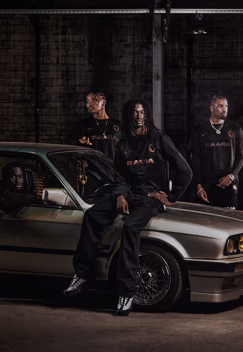 A group of young people wearing BAARA clothing next to a silver BMW