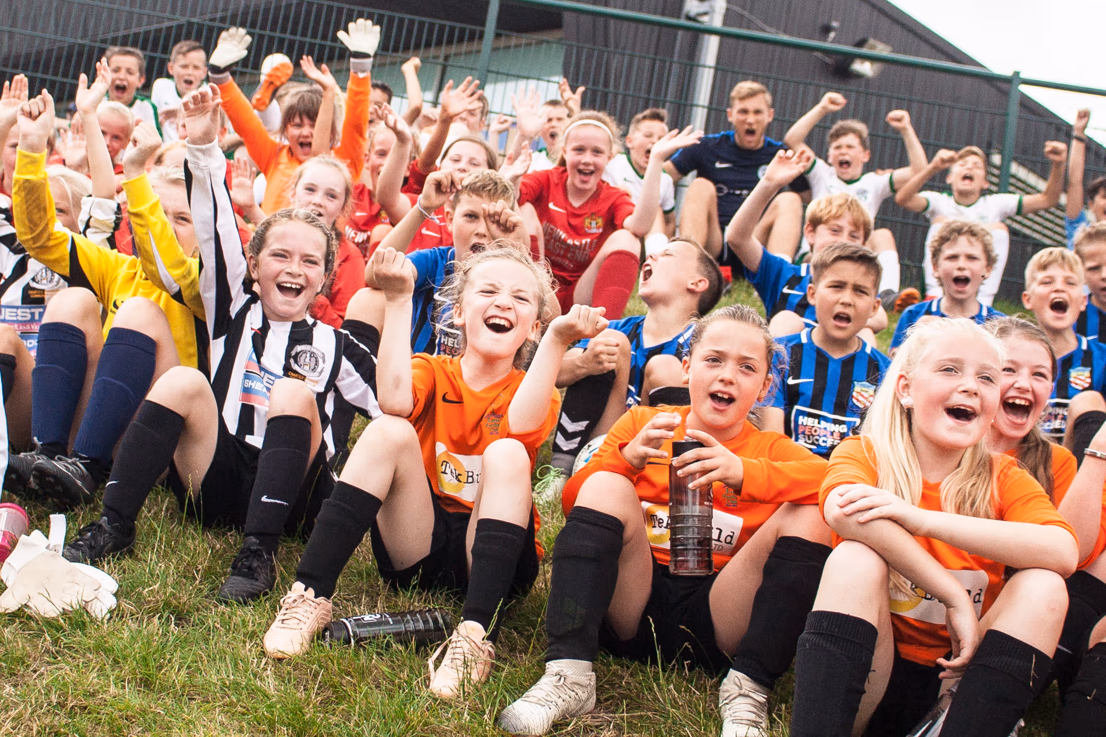 A group of happy football players kids celebrating victory with their hands in the air