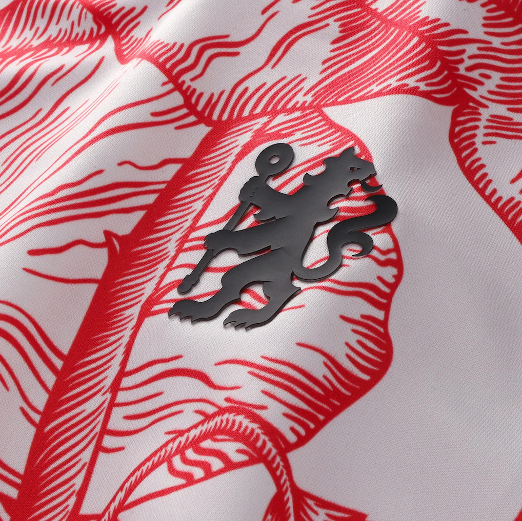 Close-up of a black lion emblem on white fabric with red line art details.