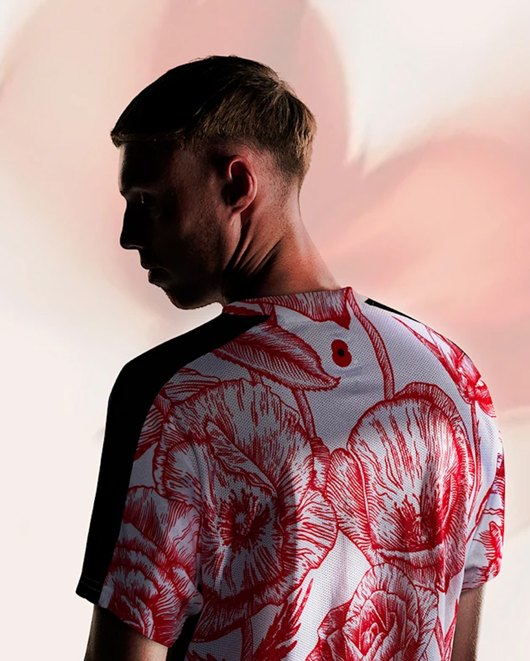 Back view of a man wearing a white and red floral patterned shirt with a poppy flower symbol on the upper back.