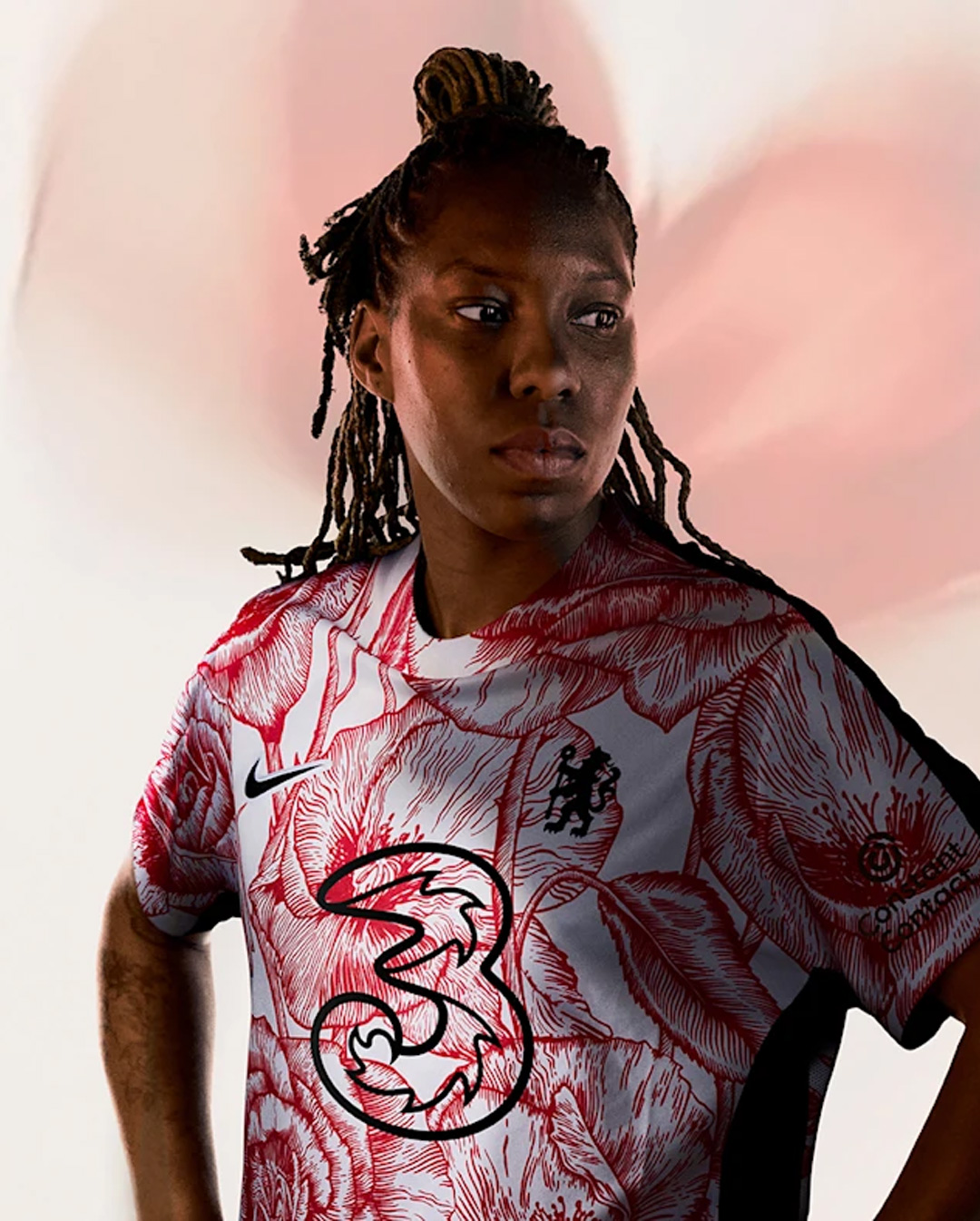 Portrait of a person with braided hair wearing a white and red floral patterned sports jersey with a large '3' logo on the front.