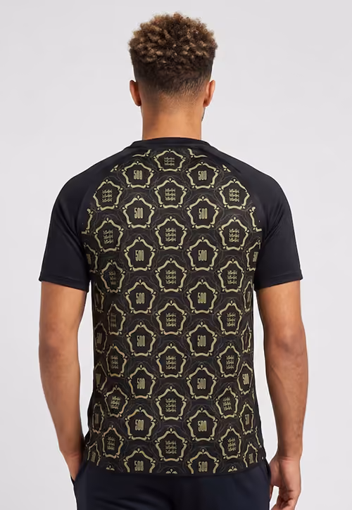 Man wearing a black t-shirt with a repetitive gold 500 and crown pattern on the back.