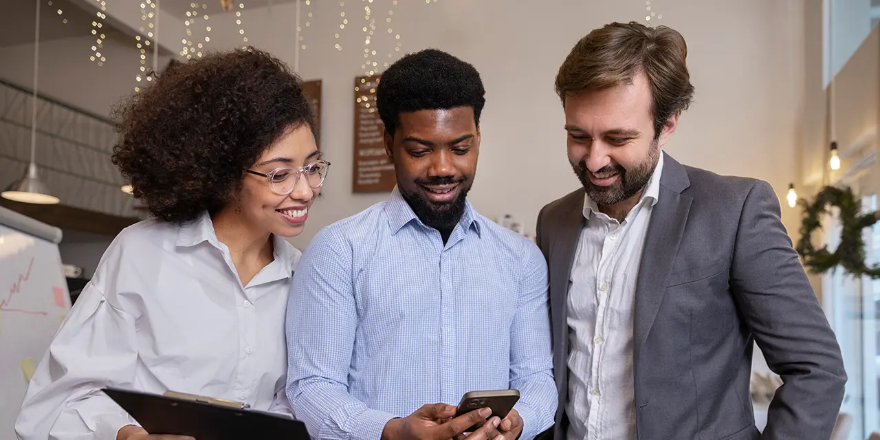 Three people looking at a cell phone.