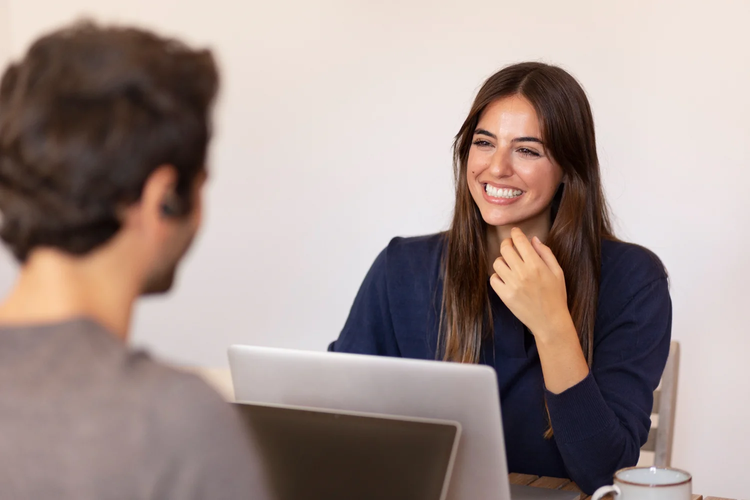 A woman smiling while talking to a man in front of a laptop