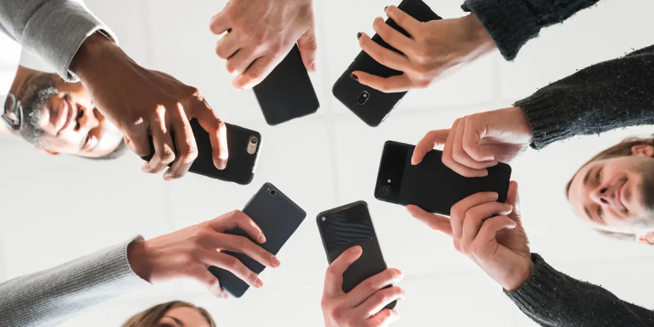 Grupo de personas que sostienen teléfonos celulares en círculo.