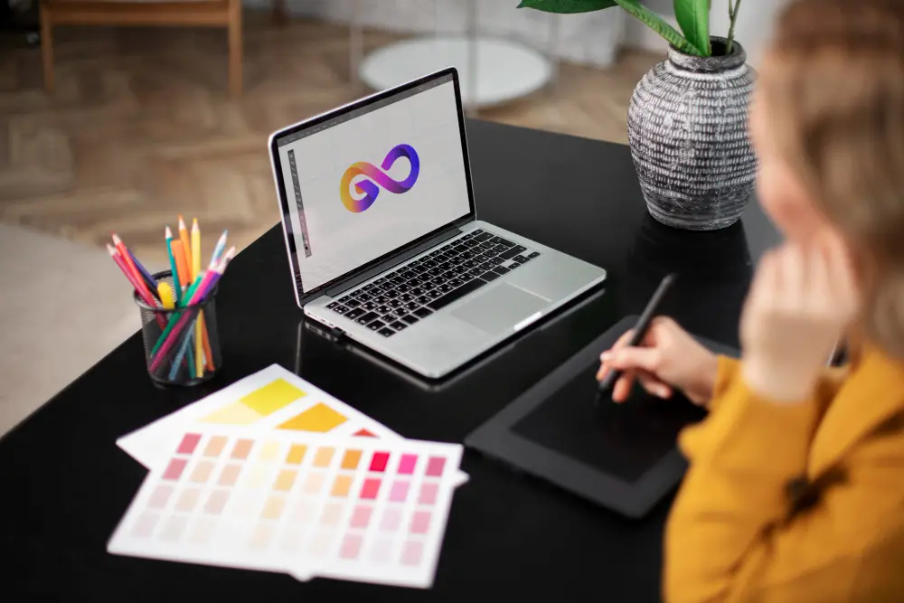 Pessoa criando logotipo digital em um laptop com paleta de cores ao lado.