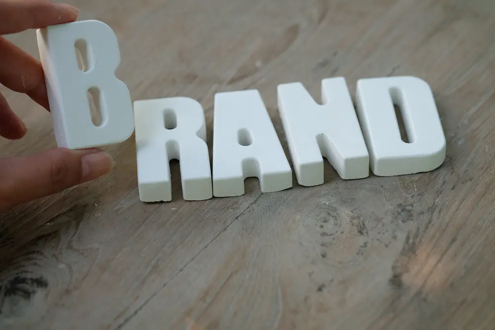 Letras formando a palavra “BRAND” sobre uma superfície de madeira.