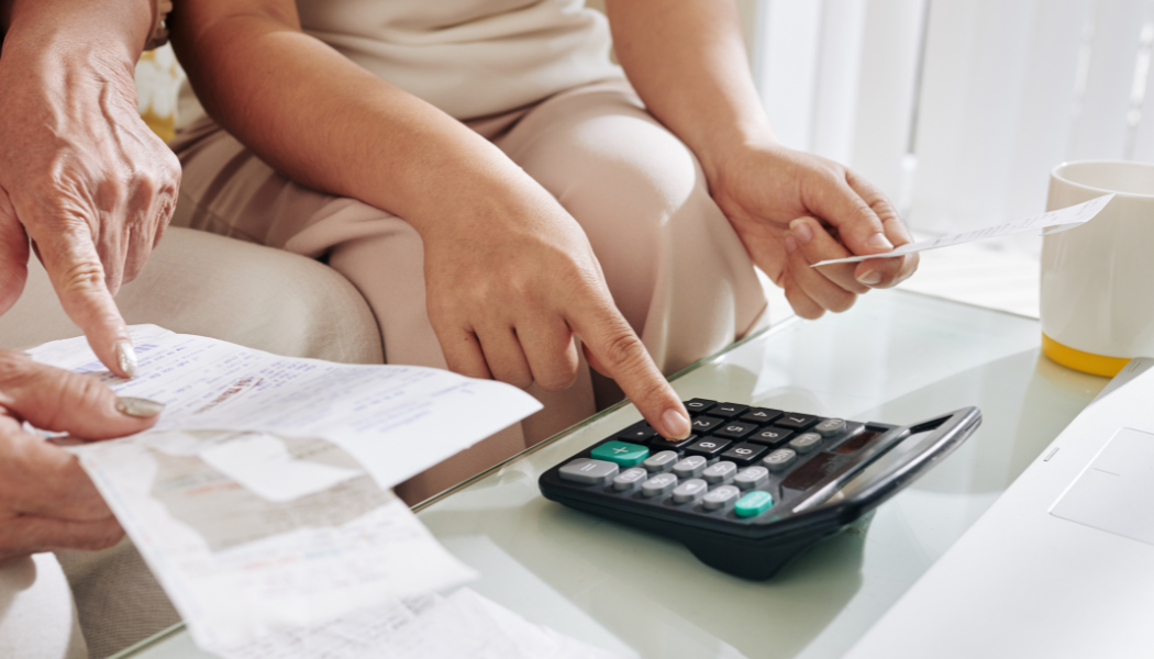 personne qui fait de la compta avec des factures et calculatrice