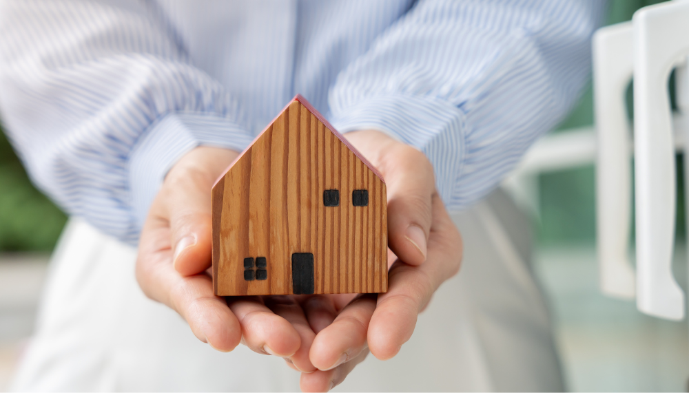 femme qui tient une maison en bois miniature