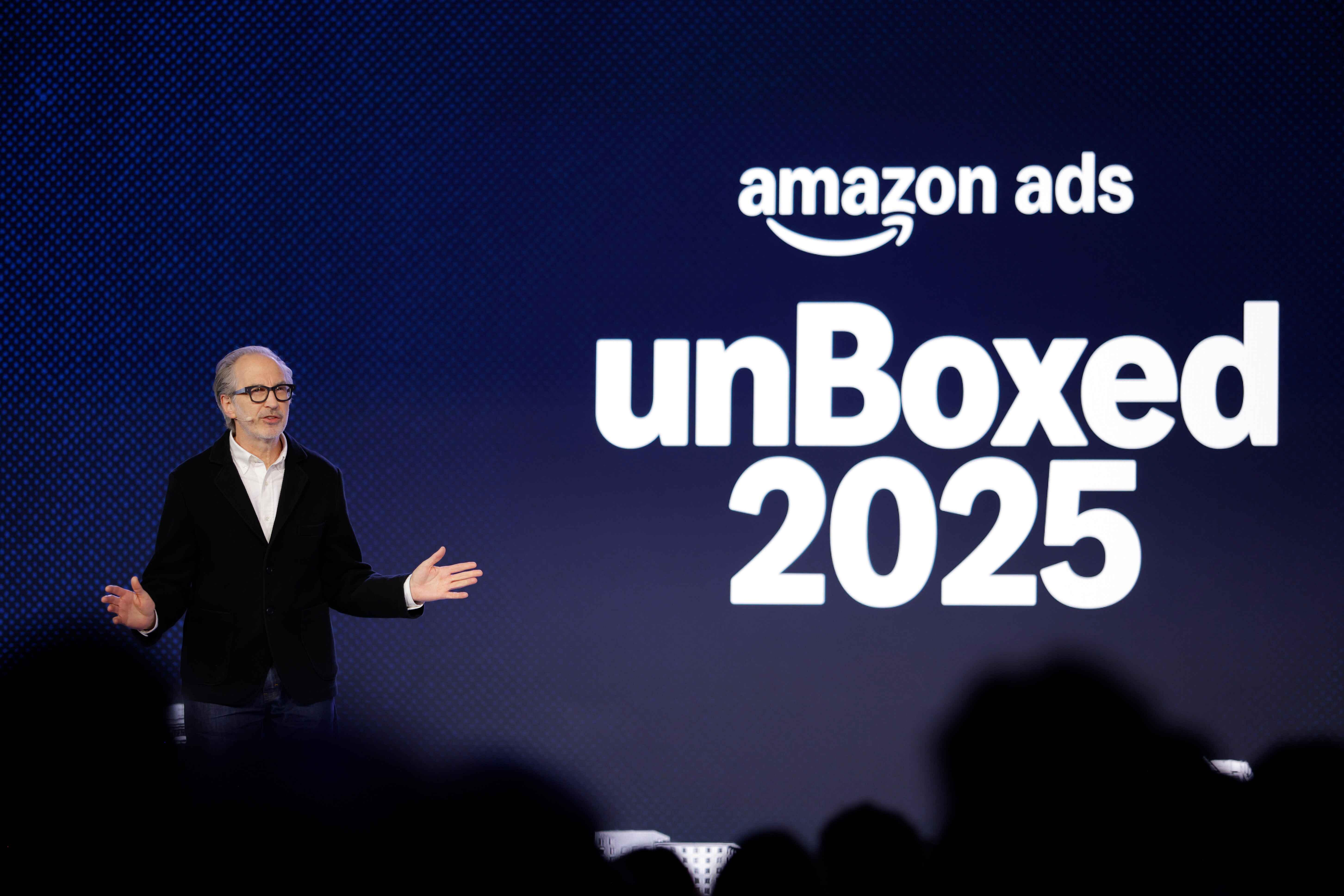  Speaker presenting at Amazon Ads unBoxed 2025 event on the blue stage with white logo and text.