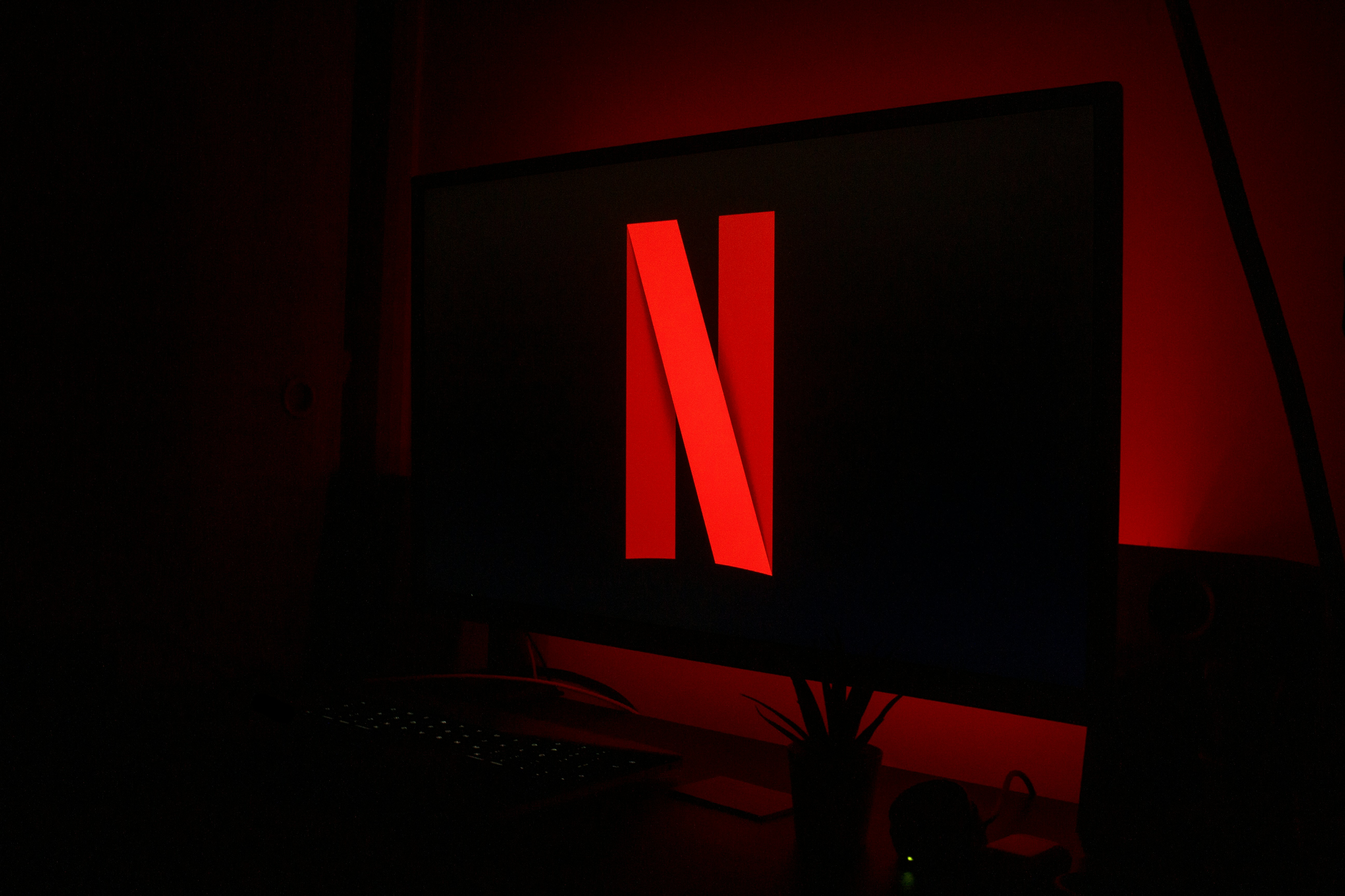Netflix logo in red on a television screen in a dark room with red ambient lighting.
