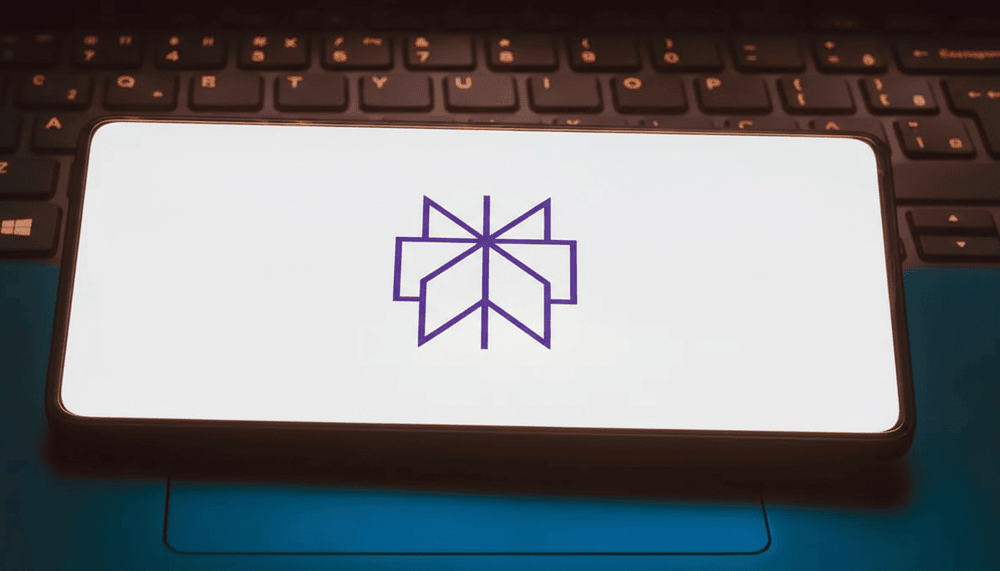 Smartphone screen displaying purple Perplexity logo on white background, placed on laptop keyboard with blue lighting.