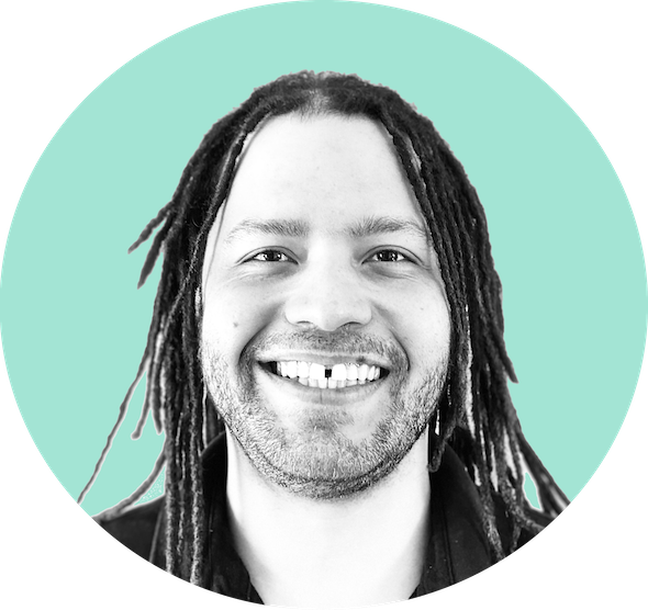 Man with long dreadlocks and a beard smiling against a light teal circular background.