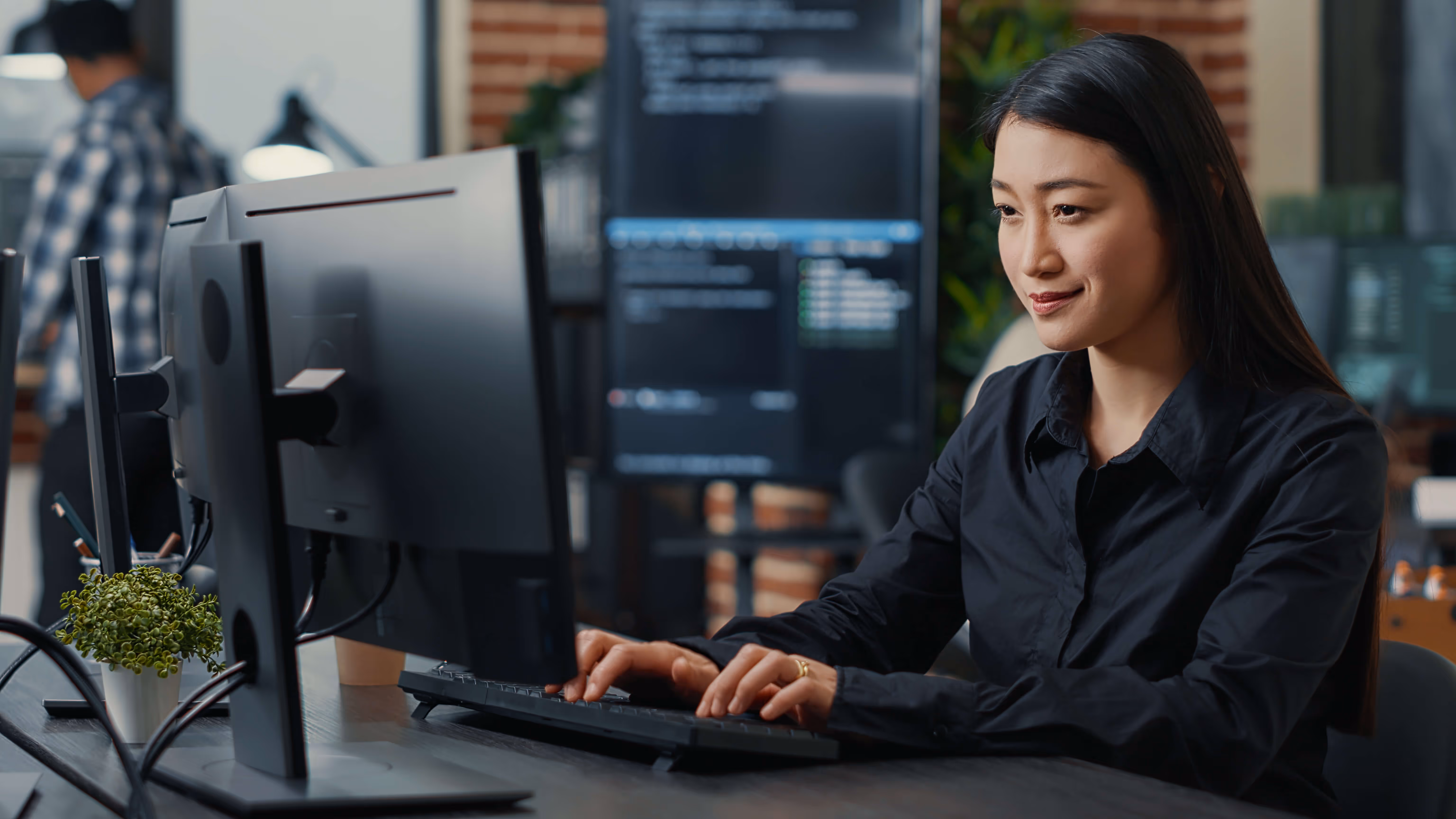 Woman working on a computer at a desk in an office.