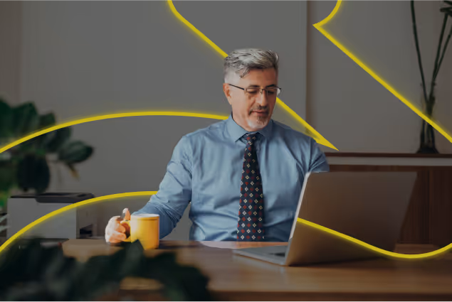a man sitting at a desk with a laptop and a cup