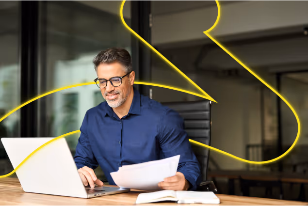 a man sitting at a desk with a laptop and papers