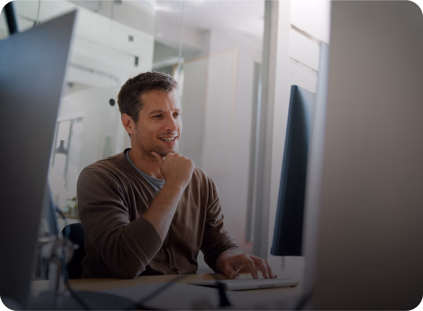 Man smiling while working on a computer in an office setting.