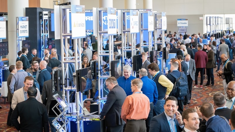 Many people gather in a room for a supply chain conference and stop at check-in stations