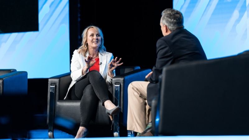 A man interviews a woman with blonde hair and a white jacket at a logistics conference