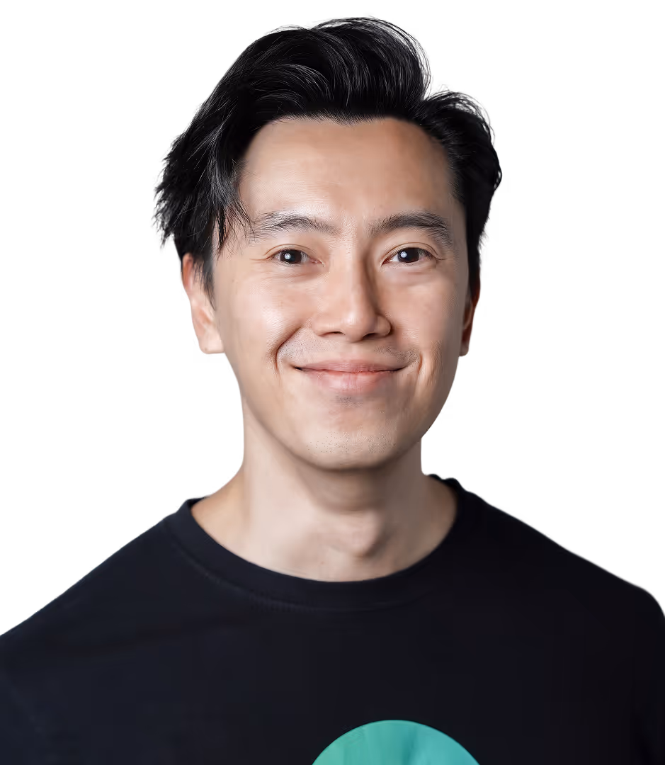 Smiling man with black hair wearing a black t-shirt with a green letter G on it.