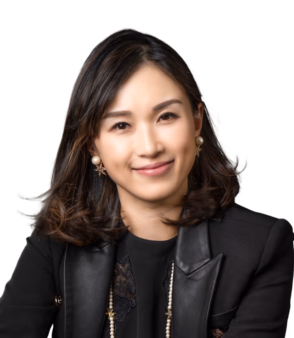 Smiling woman with shoulder-length dark hair wearing pearl earrings and a black blazer with leather lapels.