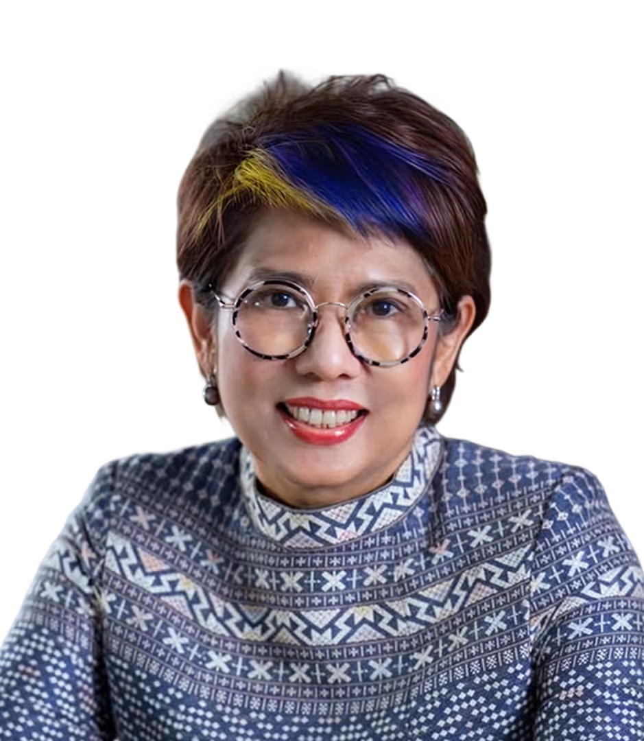 Smiling woman with short hair dyed brown with blue and yellow streaks, wearing round glasses and a patterned high-neck top.