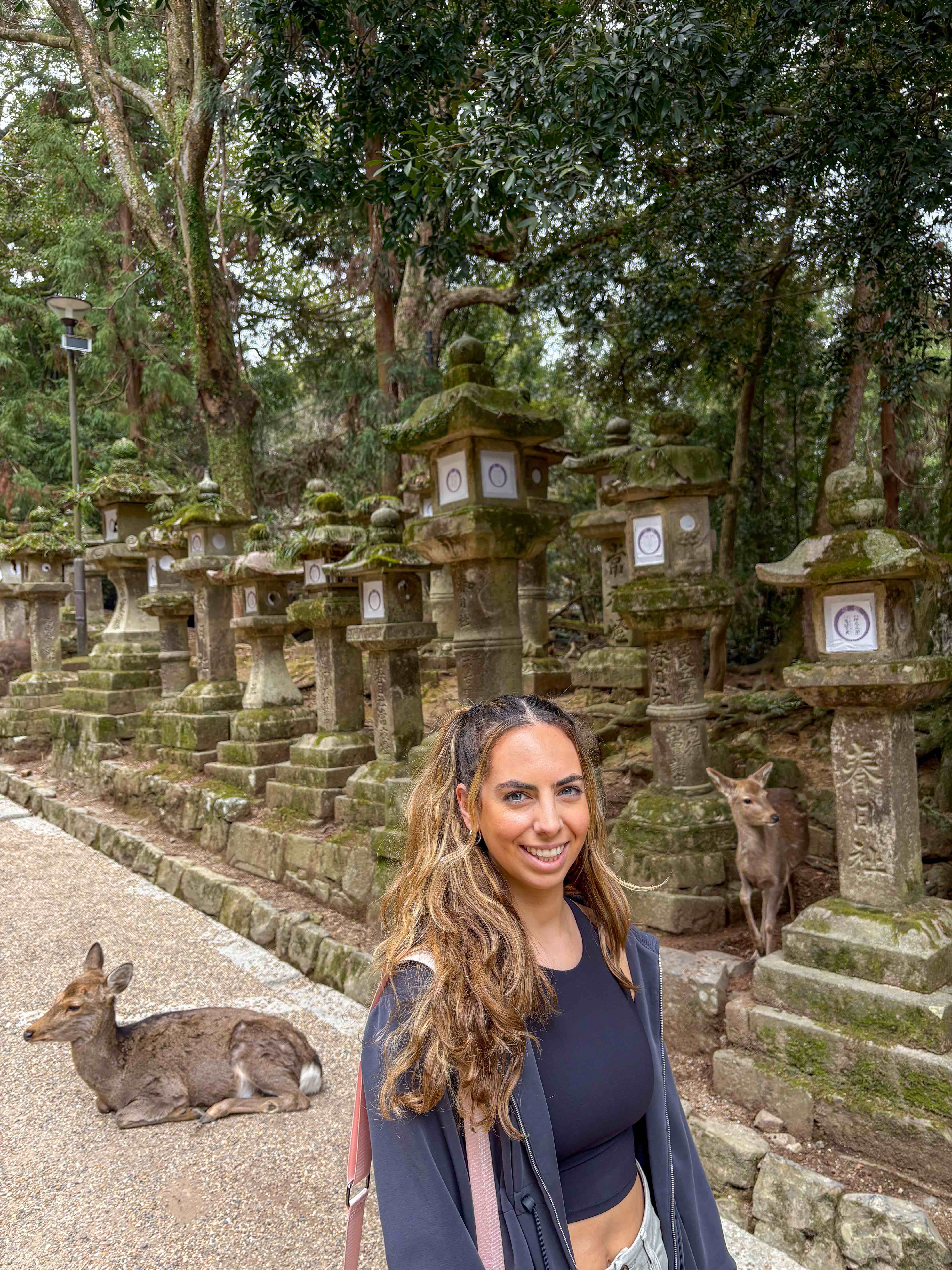 Alba from NALBA TRAVELS at Nara Park in Japan with deer walking and resting behind her
