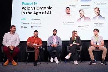 Five panelists sitting on stage at the 'Paid vs Organic in the Age of AI' conference discussion.