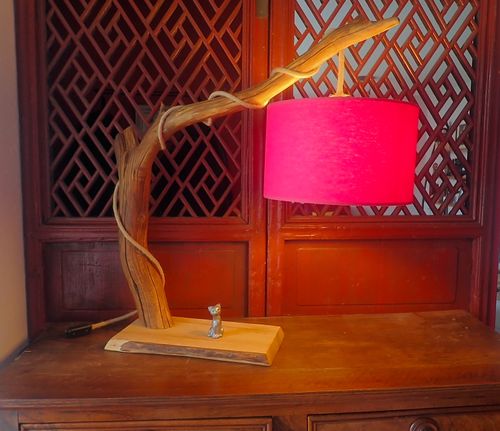 Photo d'une belle lampe artisanale en bois flotté avec un pied en bois et un abat-jour rouge.