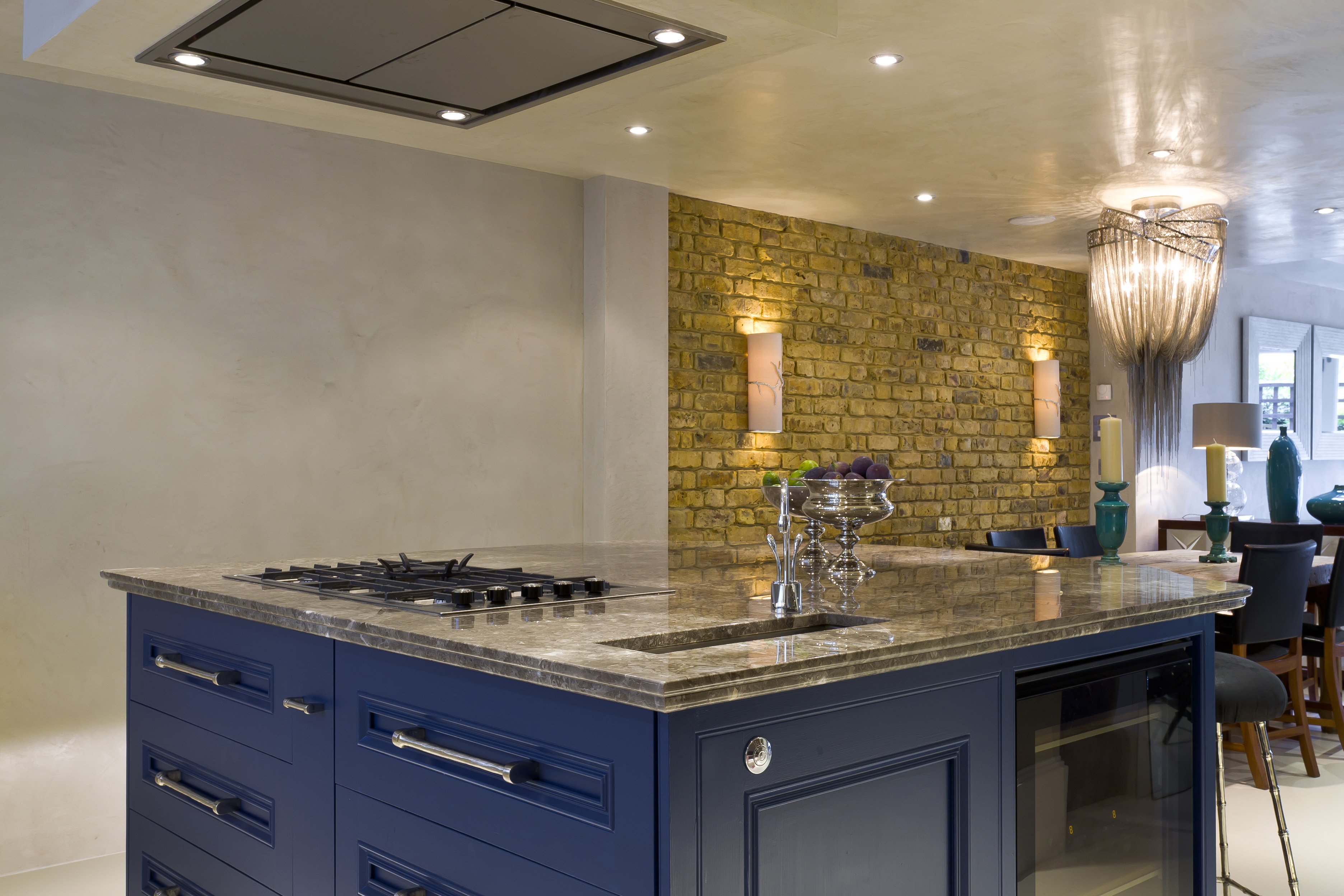 Newly built open plan kitchen with a marble top kitchen island and blue cabinets in a luxury Chelsea townhouse.
