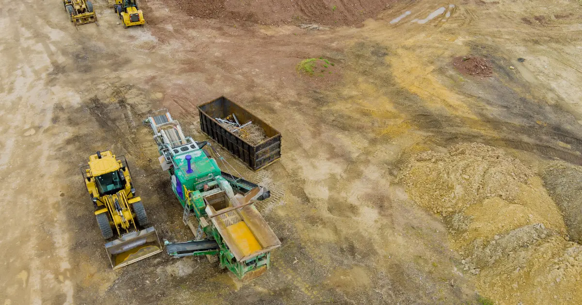 Fill dirt for construction loaded into an industrial machine at a large open site.
