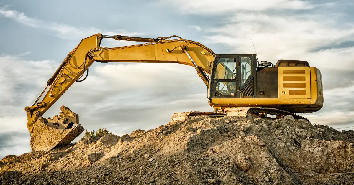 Fill dirt delivery being performed by a yellow excavator digging and moving soil on a construction mound.