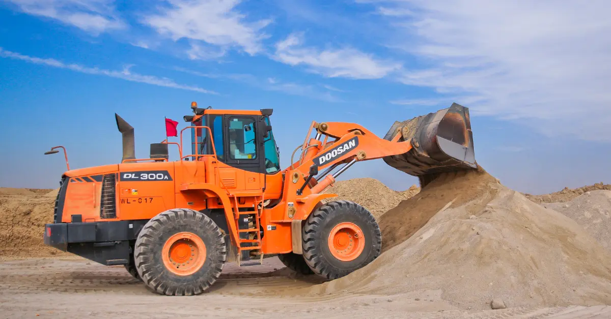Clean fill dirt being moved by an orange front loader beside a large mound at a construction site