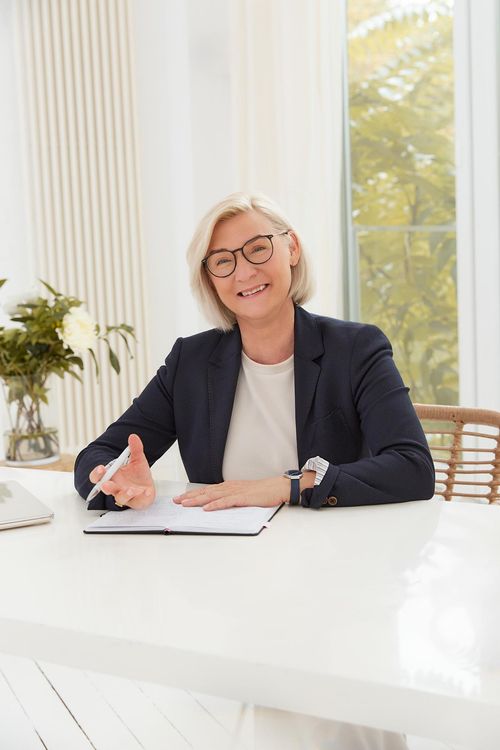 Silke Roczen von SIRO Business Mental Consulting am Schreibtisch, freundlich lächelnd