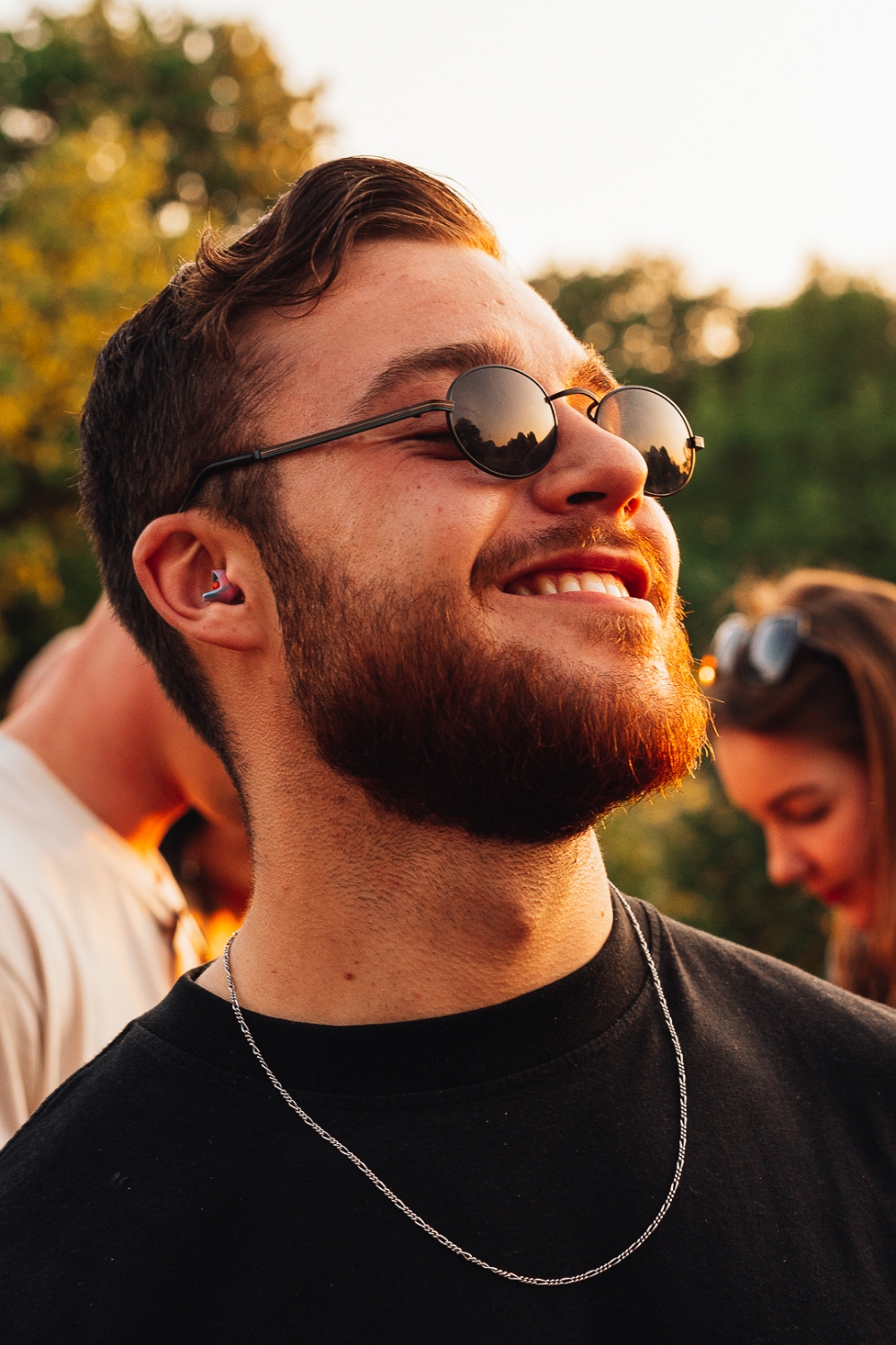 Een glimlachend meisje op een festival dat een zakje earbeanz omhoog houdt.