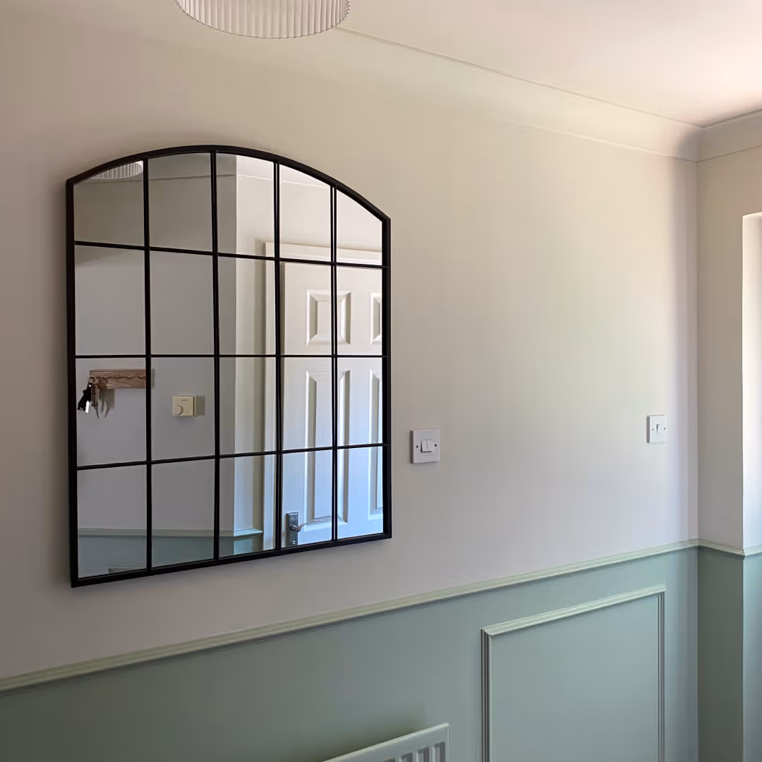 A green hallway with panelling and a black crittal mirror