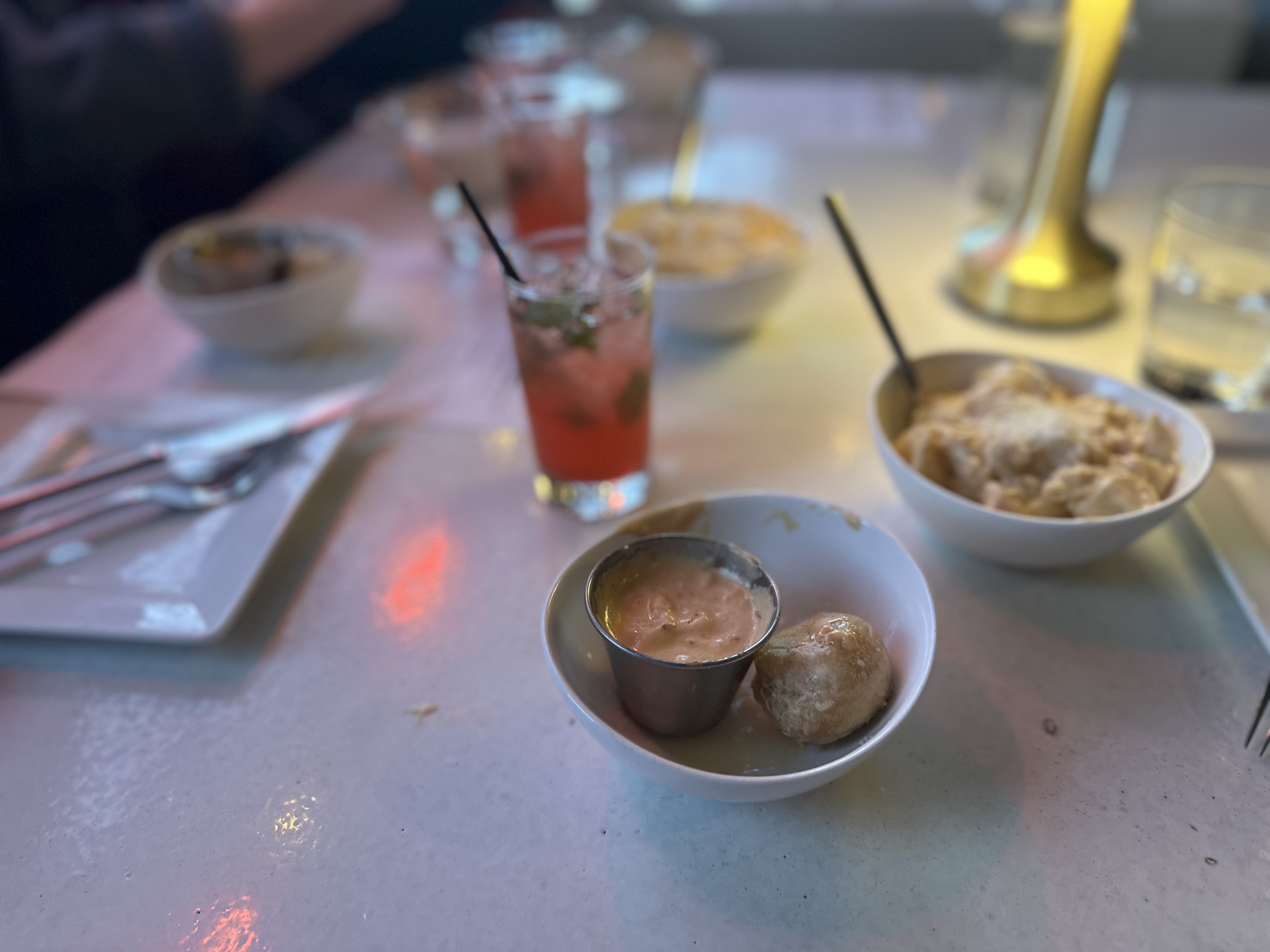 A plate of succulent shrimp with a creamy dipping sauce, served alongside cheesy macaroni and a crisp vegetable roll.