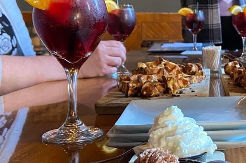 A beautifully crafted cocktail served alongside a decadent dessert and a plate of delicious gourmet food, all elegantly presented on a stylish dining table