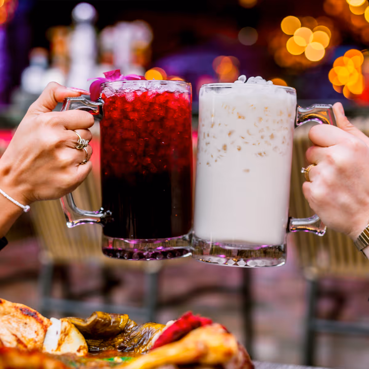 People clinking a glass mug of horchata and hibiscus and jamaica.