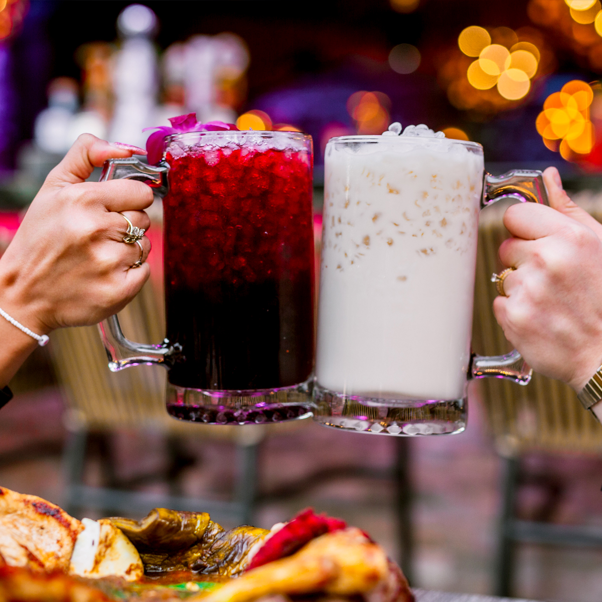 People clinking a glass mug of horchata and hibiscus and jamaica.