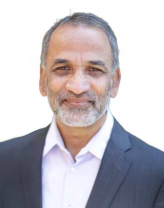 Middle-aged man with gray hair and beard smiling, wearing a dark suit jacket and white shirt.