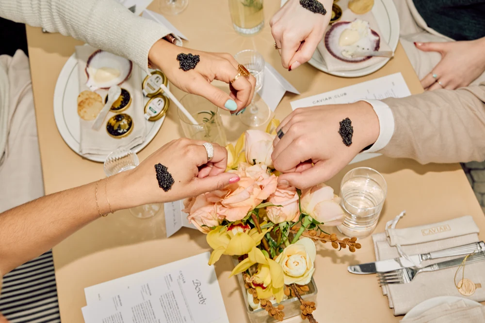 Guests sharing a caviar celebration around a floral table at Beverly