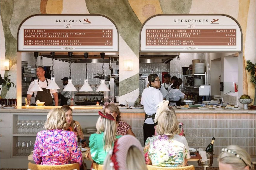 Guests at Beverly’s G.H. Mumm activation, with custom arrivals and departures boards above the kitchen